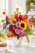 Colorful flower arrangement in a white vase on a wooden surface