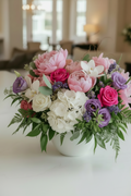 Bouquet of flowers in a white vase on a table with a blurred indoor background