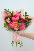 Bouquet of pink and orange flowers with green leaves on a light background