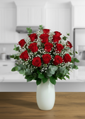 Bouquet of red roses in a white vase on a wooden table with a kitchen background